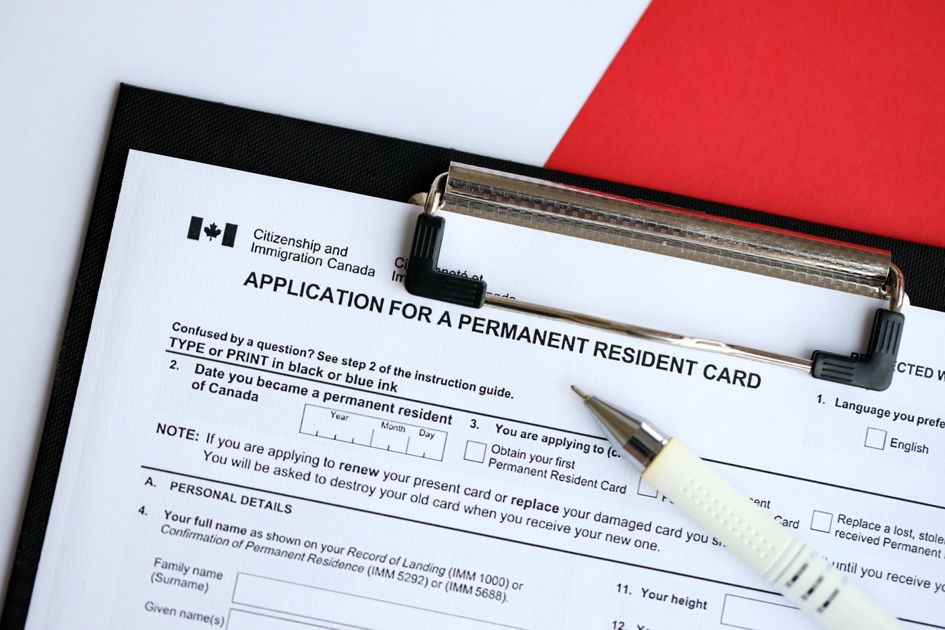 Application for permanent resident card on table with pen